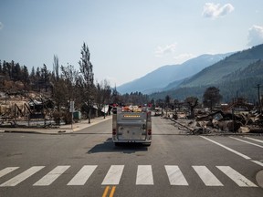 British Columbia's auditor general says his office is doing a review of the province's response to the 2021 wildfire that devastated the community of Lytton, B.C. A fire truck leads a bus down Main Street past damaged structures during a media tour in Lytton, B.C., on Friday, July 9, 2021, after a wildfire destroyed most of the village on June 30.
