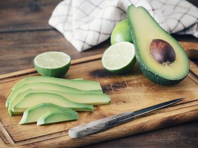 Sliced avocado and lemon lime on cutting board, on wooden background