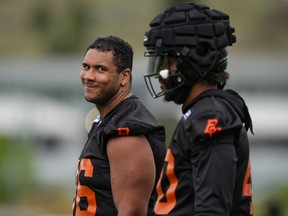 B.C. Lions defensive lineman Christian Covington, back left, smiles as he and fellow defensive lineman Pete Robertson take a break during the CFL football team's training camp in Kamloops, B.C., on Monday, May 13, 2024.
