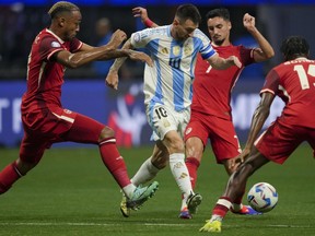 Argentina's Lionel Messi, centre, and Canada's Stephen Eustaquio battle for the ball during a Copa America Group A soccer match against Canada in Atlanta, Thursday, June 20, 2024.