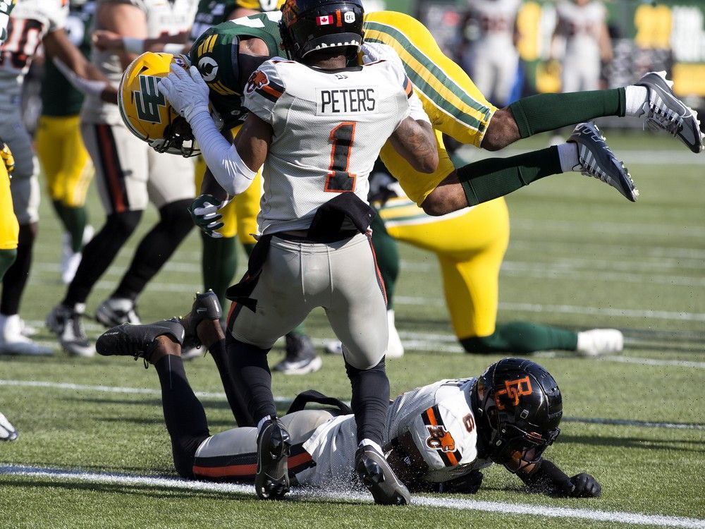The Edmonton Elks' Javon Leake (22) scores a touchdown against the B.C. Lions' Garry Peters (1) and T.J. Lee (6) during CFL action at Commonwealth Stadium, in Edmonton Sunday Aug. 11, 2024.