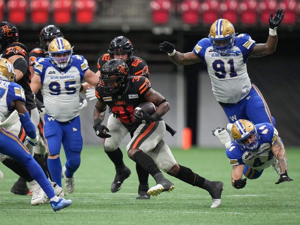 B.C. Lions' William Stanback, centre, avoids a tackle by Winnipeg Blue Bombers' Shayne Gauthier (44) as he carries the ball during the first half of a CFL football game, in Vancouver, B.C., Sunday, Aug. 18, 2024.