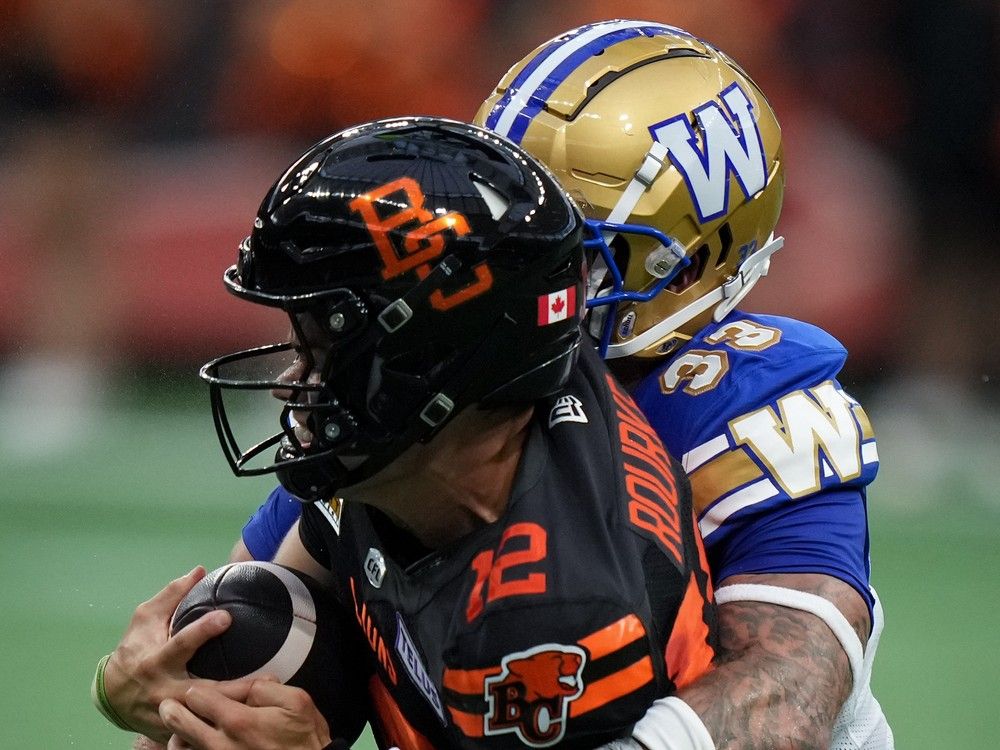 B.C. Lions quarterback Nathan Rourke, front, is tackled by Winnipeg Blue Bombers' Tony Jones as he runs the ball during the first half