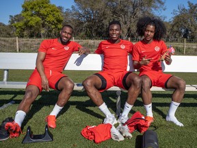 The three Canadian players sit on a bench, smiling at the camera.