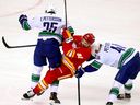 Flames centre Nazem Kadri is checked by Canucks rookie Elias Pettersson in first period Wednesday at Calgary.