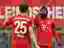 Alphonso Davies of Bayern Munich celebrates with Thomas Muller after scoring his team's fourth goal during a 2020 Bundesliga game