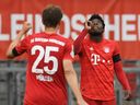 Alphonso Davies of Bayern Munich celebrates with Thomas Muller after scoring his team's fourth goal during a 2020 Bundesliga game