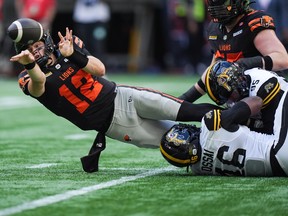 B.C. Lions quarterback Nathan Rourke (12) throws the ball away as Hamilton Tiger-Cats' Julian Howsare (95) and Philip Ossai (46) nearly sack him during the first half of a CFL football game, in Vancouver, on Sunday, July 27, 2025.