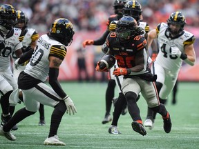 B.C. Lions' James Butler (20) runs the ball past Hamilton Tiger-Cats' Stavros Katsantonis (30) during the first half of a CFL football game, in Vancouver, on Sunday, July 27, 2025.