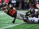 B.C. Lions quarterback Nathan Rourke (12) throws the ball away as Hamilton Tiger-Cats' Julian Howsare (95) and Philip Ossai (46) nearly sack him during the first half of a CFL football game, in Vancouver, on Sunday, July 27, 2025.