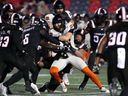 B.C. Lions quarterback Nathan Rourke (centre left) is tackled by Ottawa Redblacks linebacker Jovan Santos-Knox (centre right) during first half CFL football action in Ottawa on Friday, Sept. 5, 2025.