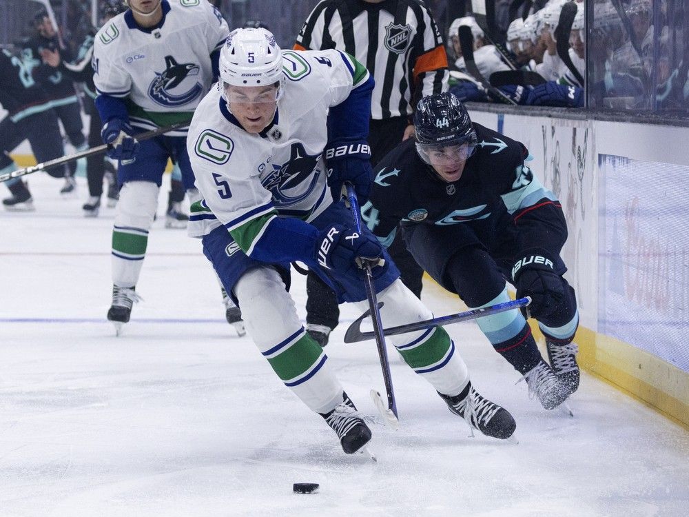 Vancouver Canucks defenceman Tom Willander (5) and Seattle Kraken forward Jake O'Brien vie for the puck during a preseason game this year.