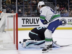 Vancouver Canucks right wing Chase Stillman (61) scores against Seattle Kraken goaltender Joey Daccord, bottom, during the second period of a preseason NHL hockey game Sunday, Sept. 21, 2025, in Seattle.