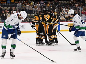 Connor Dewar #19 of the Pittsburgh Penguins celebrates with teammates after scoring a goal in the first period against the Vancouver Canucks at PPG PAINTS Arena on October 21, 2025 in Pittsburgh.