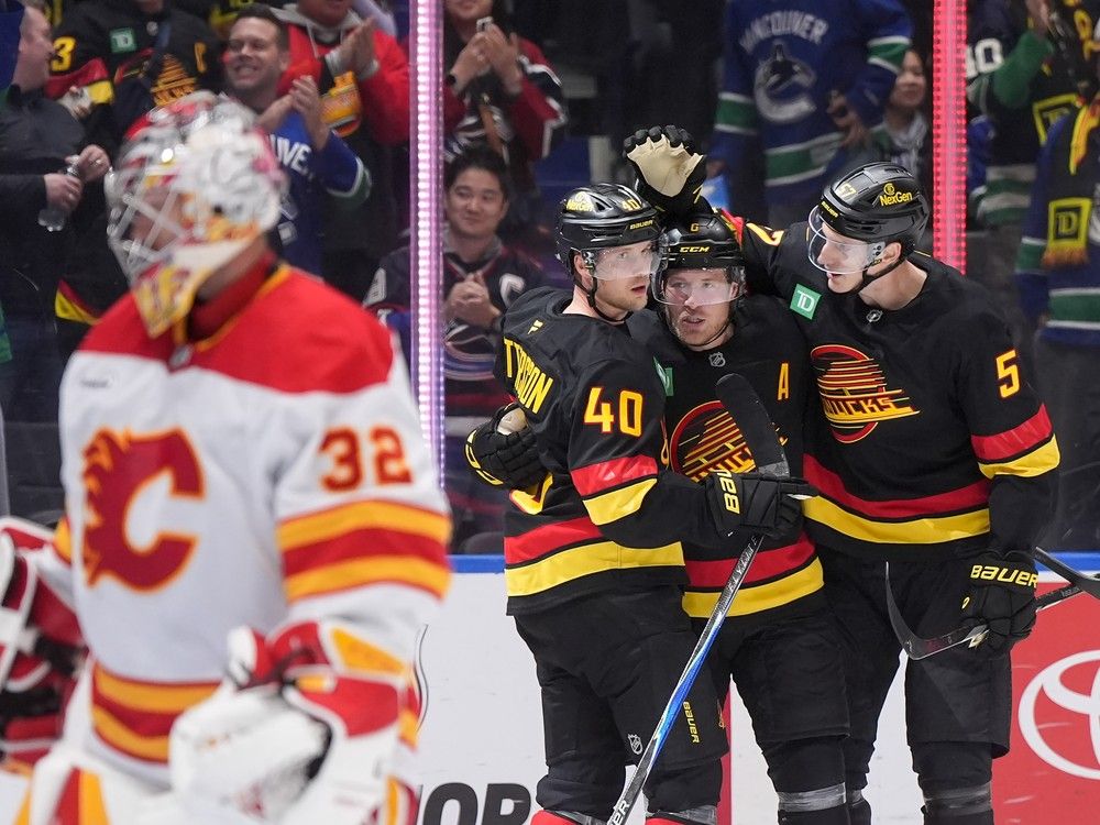 Vancouver Canucks' Elias Pettersson, Brock Boeser and Tyler Myers celebrate Pettersson's goal against Calgary Flames goalie Dustin Wolf in Vancouver, on October 9.