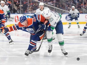 Elias Pettersson (40) and Edmonton Oilers' Ty Emberson (49) battle for the puck during the third period in Edmonton on Saturday, October 11, 2025.