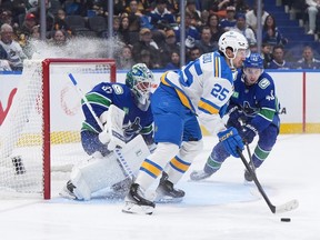 St. Louis Blues’ Jordan Kyrou (25) passes the puck in front of Canucks goalie Kevin Lankinen (32) and Quinn Hughes (43) during the second period