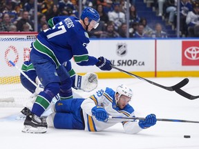 Tyler Myers (57) and St. Louis Blues' Nathan Walker (26) vie for the puck during the first period