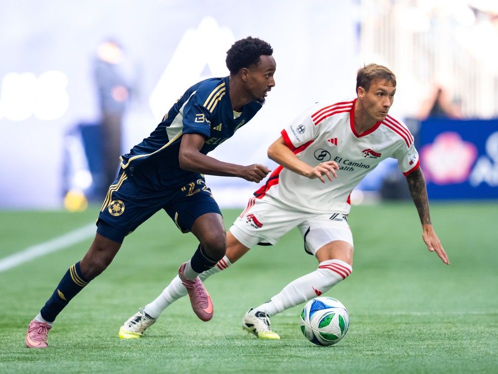 Vancouver Whitecaps' Ali Ahmed (22) and San Jose Earthquakes' Benji Kikanovic, right, vie for the ball during the first half of an MLS soccer match in Vancouver, on Sunday, October 5, 2025.