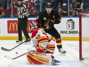 Brock Boeser tries to get his stick on the rebound after goalie Dustin Wolf of the Calgary Flames made the initial save during the second period