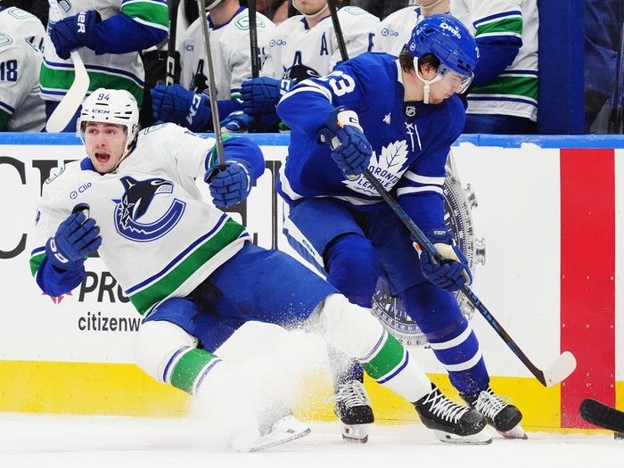 Vancouver Canucks' Linus Karlsson (94) and Toronto Maple Leafs' Matthew Knies (23) collide during first period NHL hockey action in Toronto on Saturday, Jan. 10, 2026.