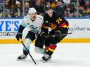 Defenceman Zeev Buium of the Vancouver Canucks gets a leg up on forward Chandler Stephenson of the Seattle Kraken during second period Saturday at Rogers Arena.