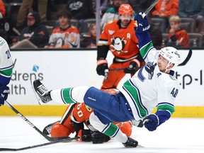 Elias Pettersson is tripped by Tyson Hinds #60 of the Anaheim Ducks during the first period