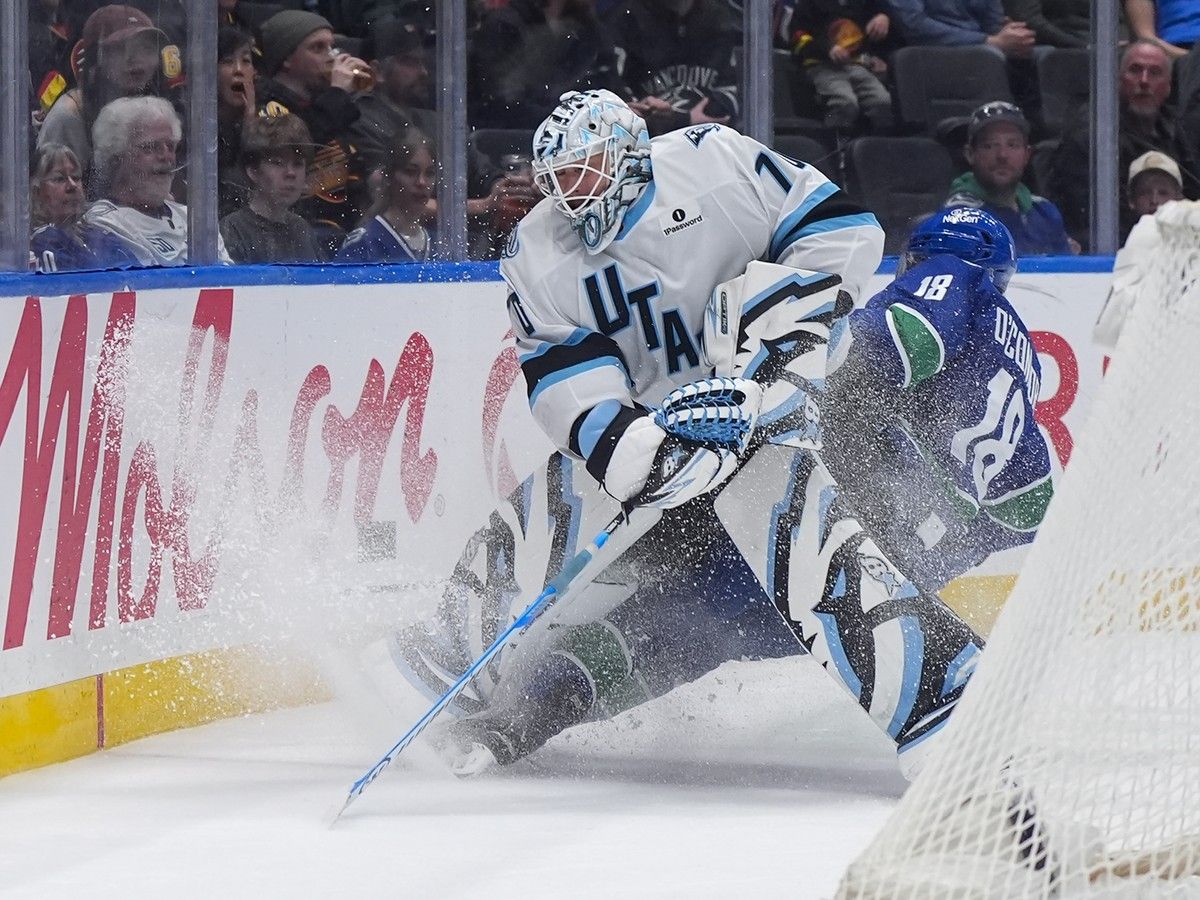 Utah Mammoth goalie Karel Vejmelka and Vancouver Canucks' Drew O'Connor collide behind the net.