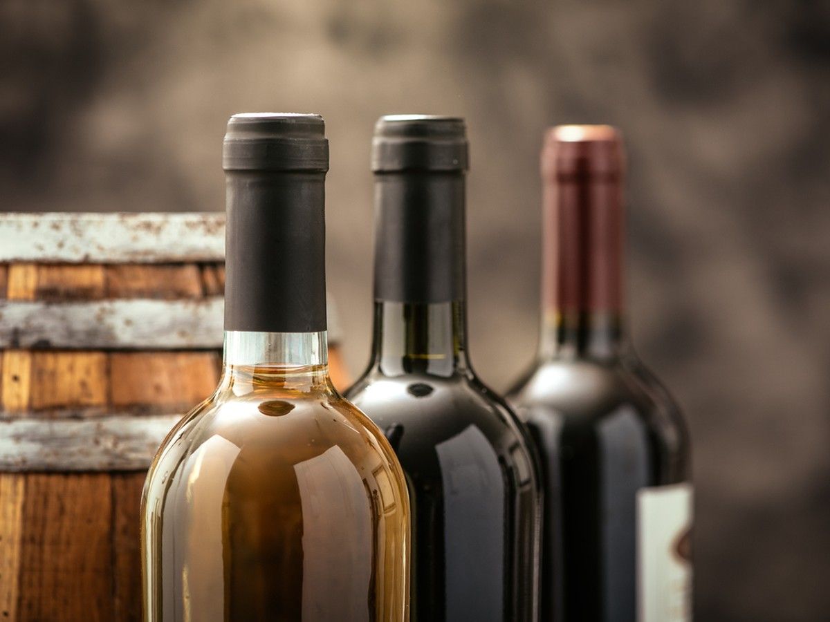 Expensive wine bottles collection and wooden barrel in the cellar.