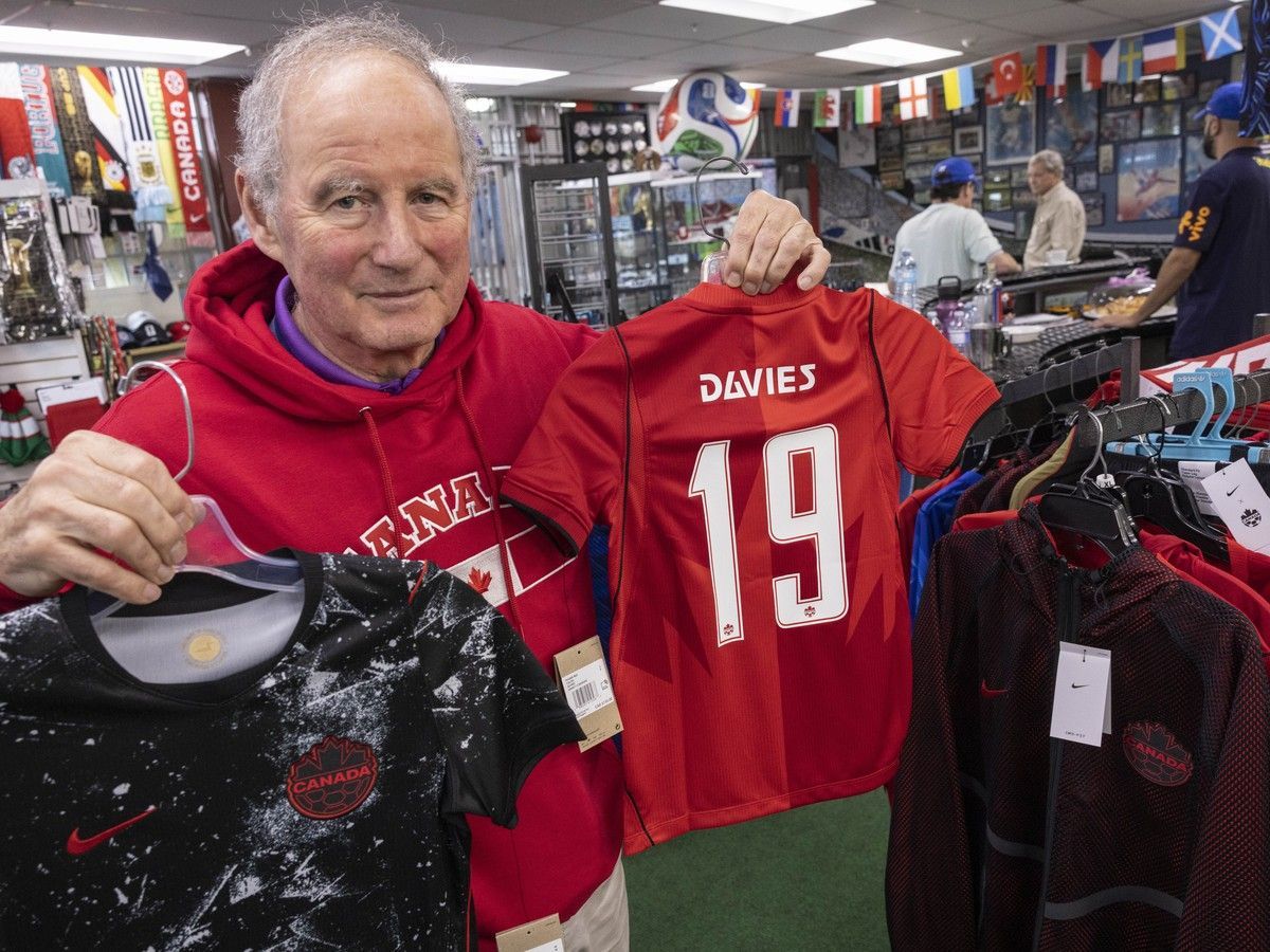 Ferruccio Susin, owner of North American Sports in Vancouver, holds team Canada soccer jerseys at his store Friday.