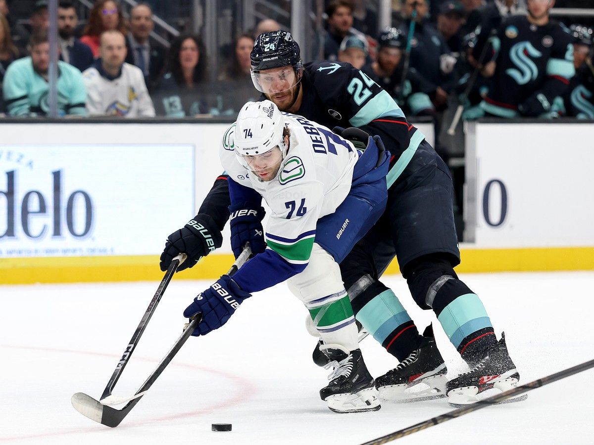 Jamie Oleksiak of the Kraken ties up the Canucks' Jake DeBrusk during a March 1, 2025, game at Climate Pledge Arena in Seattle.