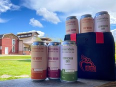 A line of Merridale cider cans against a backdrop of blue sky and clouds.