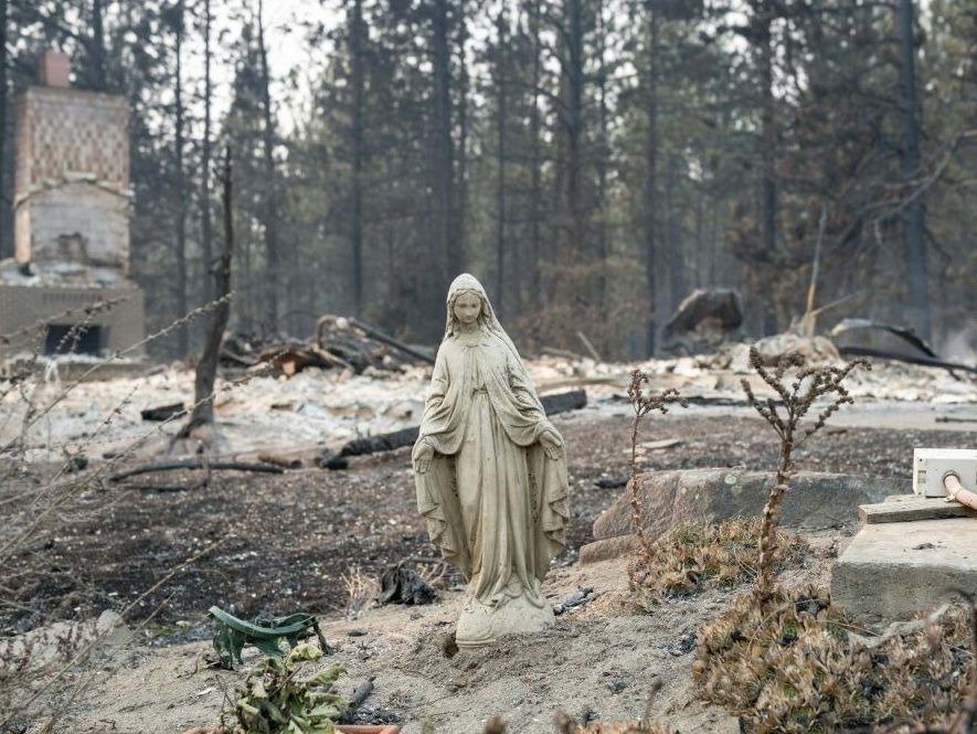 A Virgin Mary statue remains untouched in front of a burned out residential home in the Balboa neighborhood of Spokane, Washington, on August 2, 2026.