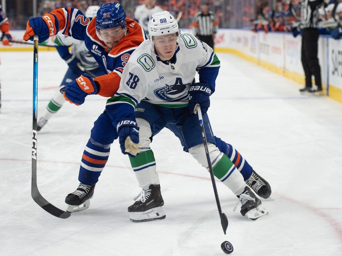 Jonathan Lekkerimaki protects the puck against Vasily Podkolzin of the Edmonton Oilers at Rogers Place in Edmonton on Tuesday night.