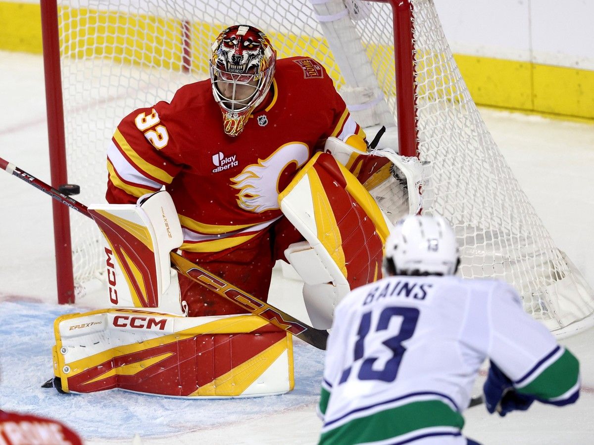 Arshdeep Bains scores the Canucks' lone goal against Calgary Flames goalie Dustin Wolf during the third period in a 3-1 pre-season loss at the Scotiabank Saddledome in Calgary on Tuesday night.