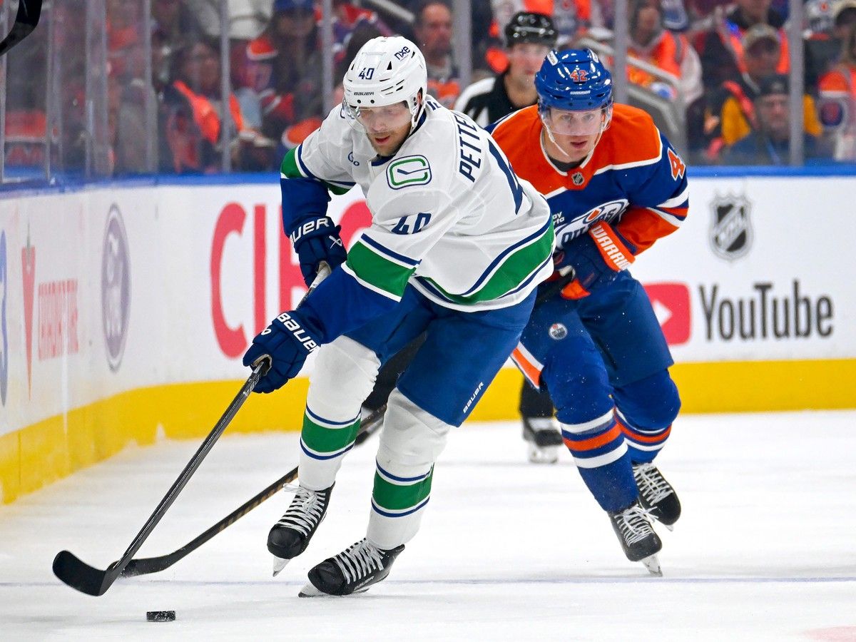 Elias Pettersson carries the puck through the neutral zone with Kasperi Kapanen of the Oilers in pursuit during the third period in Edmonton on Tuesday night