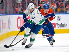 Elias Pettersson carries the puck through the neutral zone with Kasperi Kapanen of the Oilers in pursuit during the third period in Edmonton on Tuesday night