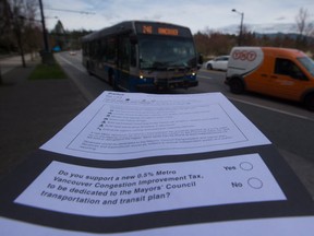 A ballot for the proposed transit tax is displayed as a bus passes by on West Georgia Street in Vancouver, B.C., in March. Referendum ballots were sent out to Metro Vancouver voters last month with mail-in voting to take place until May 29 on a proposed 0.5% increase in the PST to fund transit projects.