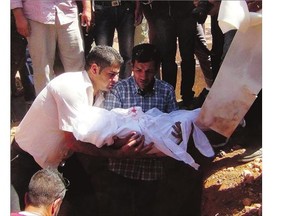 Abdullah Kurdi, centre, holds the body of his son who drowned off the Turkish coast, during a funeral ceremony in Kobani, Syria, on Friday. Three-year-old Alan, his brother, and his mother were buried in front of a large crowd. 'Everyone was very sad and crying,' said one local journalist.