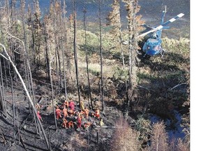 An aerial view of a helicopter delivering military re ghters to a burned forest near Weyakwin on Wednesday.