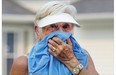 Anne Van Impe covers up and tries not to breathe the smoke in the air while out walking her daughter's dog Monday on Russell Road.