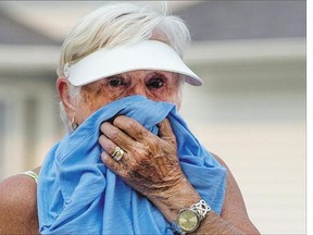 Anne Van Impe covers up and tries not to breathe the smoke in the air while out walking her daughter's dog Monday on Russell Road.