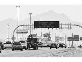 An Arizona Department of Transportation sign gives a hotline number for information on the recent freeway shootings as motorists pass.