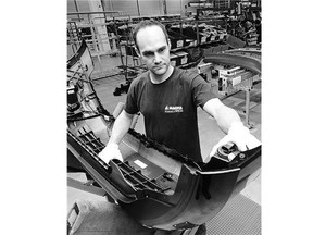 An assembler carries a front bumper at a Magna plant in Meerane, Germany. One of many Magna plants around the world, it supplies plastic parts to nearby Volkswagen.