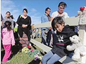 Avary Cyr, bottom right, and others look down during a prayer at a memorial walk for the Regina Indian Industrial School cemetery west of Regina Saturday. Various First Nations want the cemetery to be protected as a heritage site.