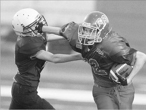 Bantam Babineau Warriors' Erik Humphreys, left, is straight armed by River Rider Kyle Adams during a punt return in third-quarter Kinsmen Tackle Football action at the SMF Field on Wednesday.