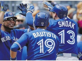 Blue Jays' Edwin Encarnacion, left, greets Justin Smoak and Jose Bautista after Smoak hit a grand slam against the Yankees on Saturday.