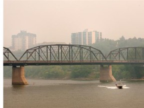 A boat travels down the South Saskatchewan River past the Traffic Bridge.