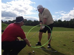 Brad Birnie helps Basil Hughton with his golf swing.