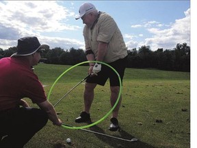 Brad Birnie helps Basil Hughton work on improving his golf swing.
